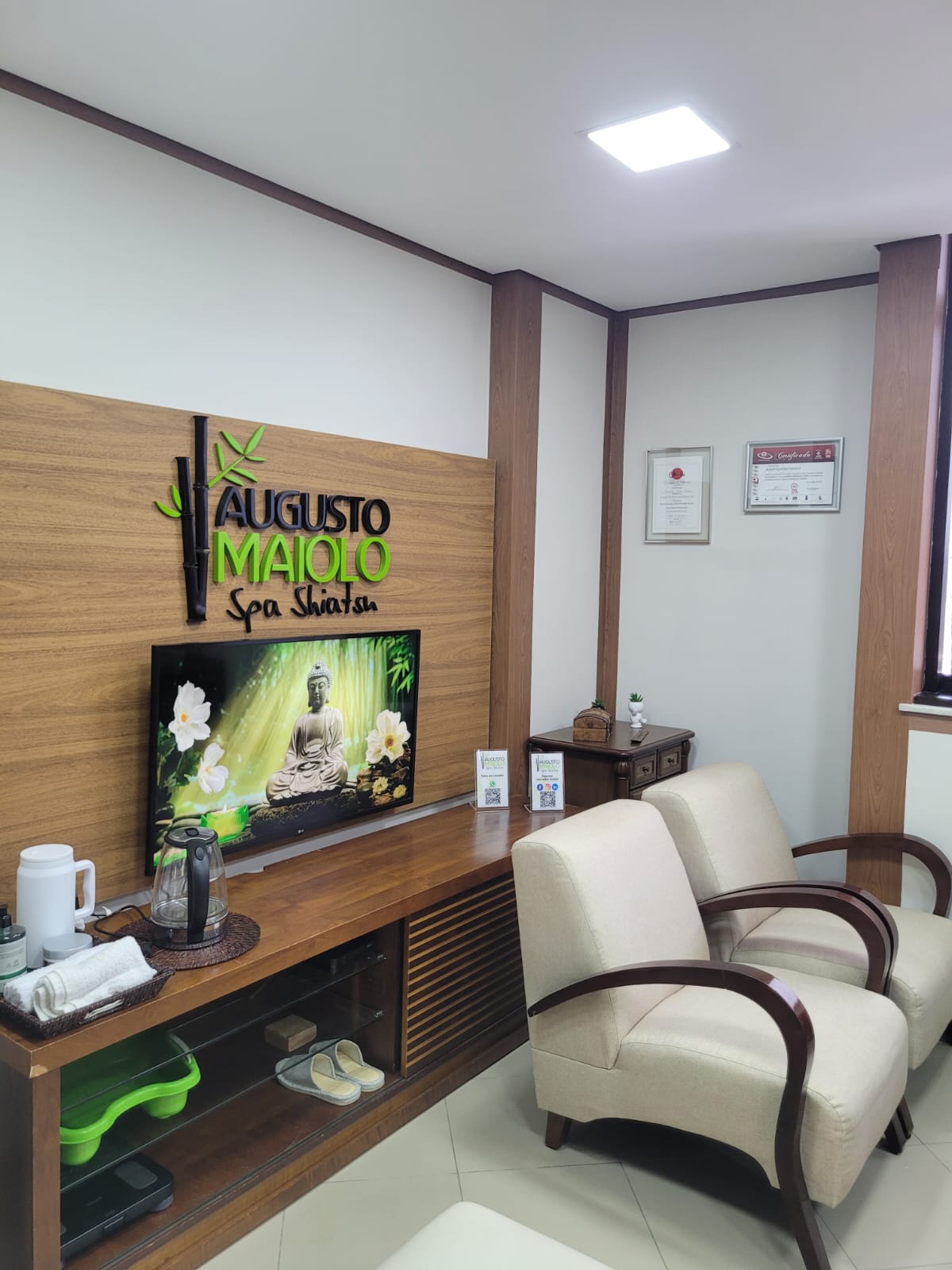 Sala de espera do Augusto Maiolo Spa Shiatsu com poltronas, letreiro e certificados