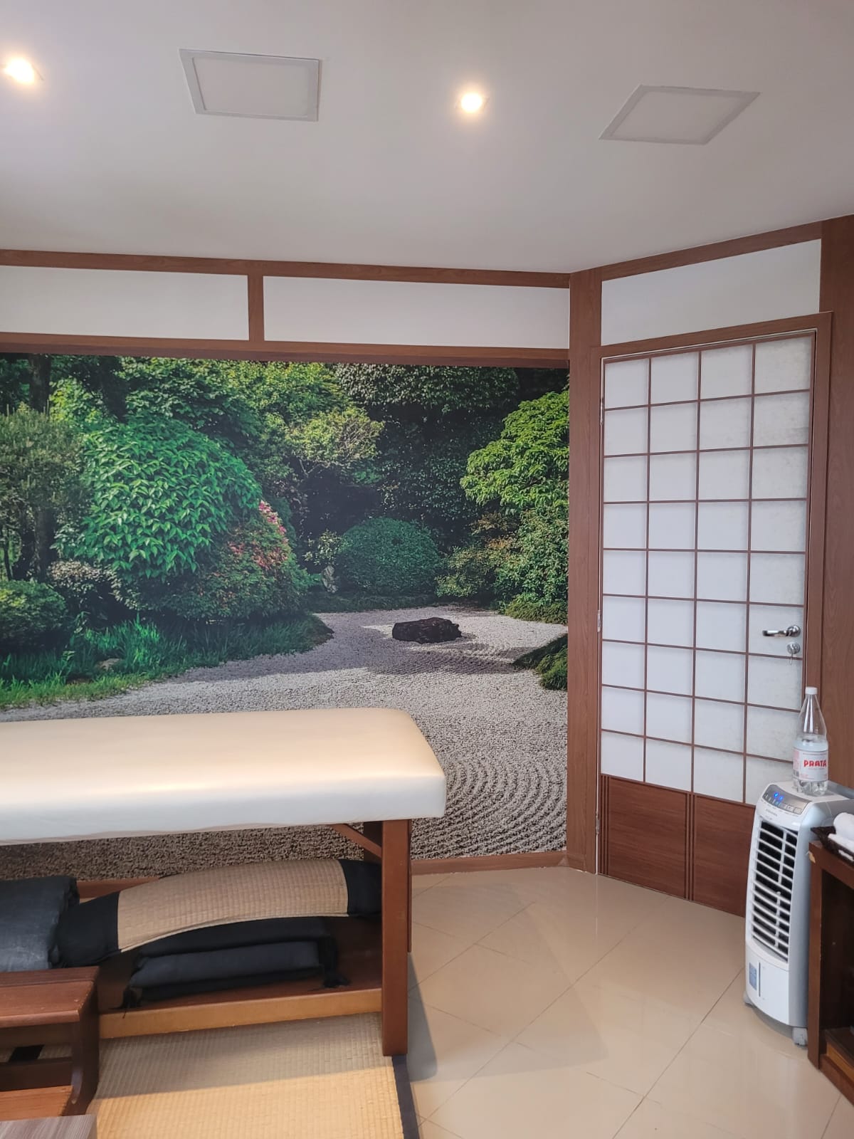 Sala de massagem com porta shoji e mural de jardim zen